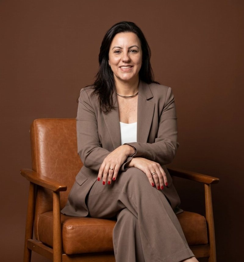 Franciely Ribeiro, psicóloga clínica, sentada em uma poltrona de couro, sorrindo.